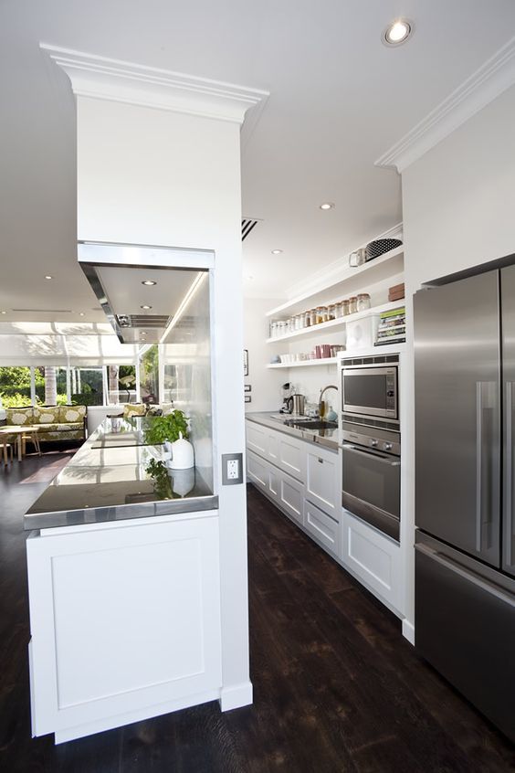 a modern kitchen with stainless steel appliances and white cabinetry, along with hardwood flooring