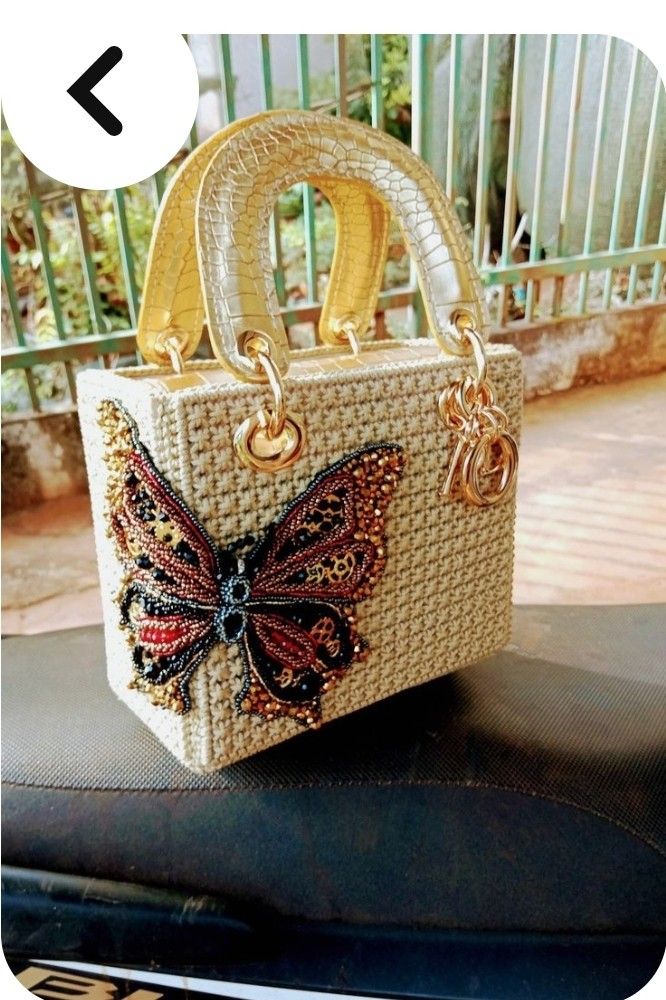 a handbag with a butterfly on it sitting on top of a seat in front of a fence