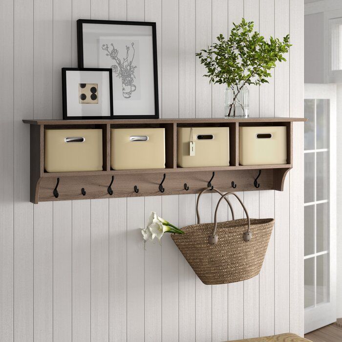 a wooden shelf with baskets and pictures on it next to a wall mounted coat rack