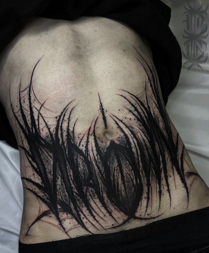 the back of a woman's stomach with black ink on it and hair blowing in the wind