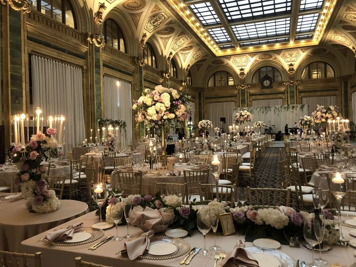 the tables are set up for a formal dinner in an ornate setting with chandeliers and floral centerpieces