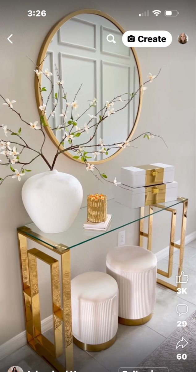 a white vase sitting on top of a table next to two stools and a mirror