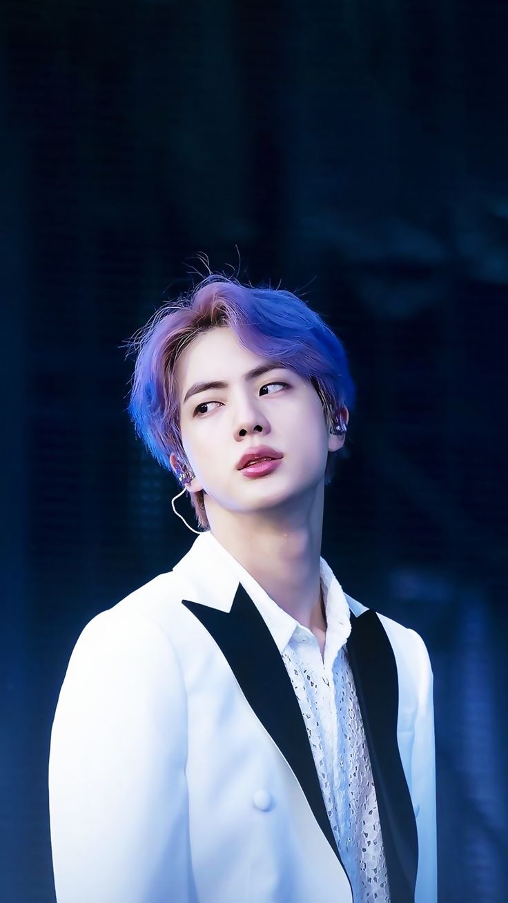 a man with blue hair wearing a white shirt and black tie standing in front of a dark background