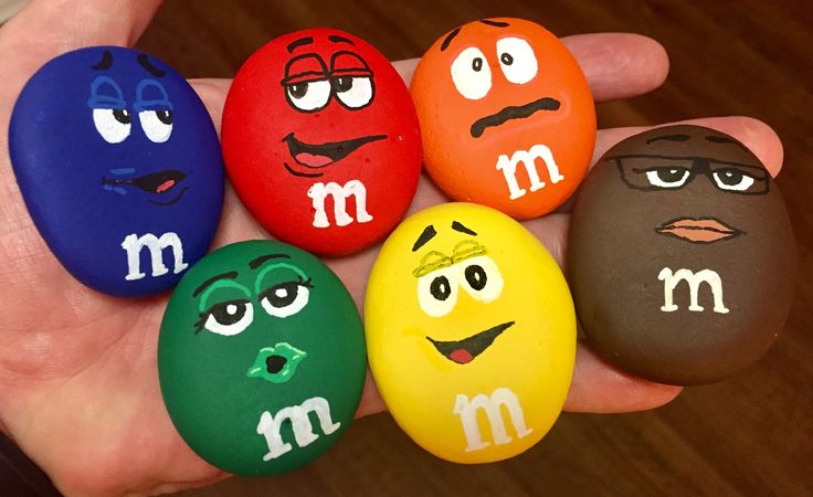 five different colored rocks with faces painted on them in the shape of m and m