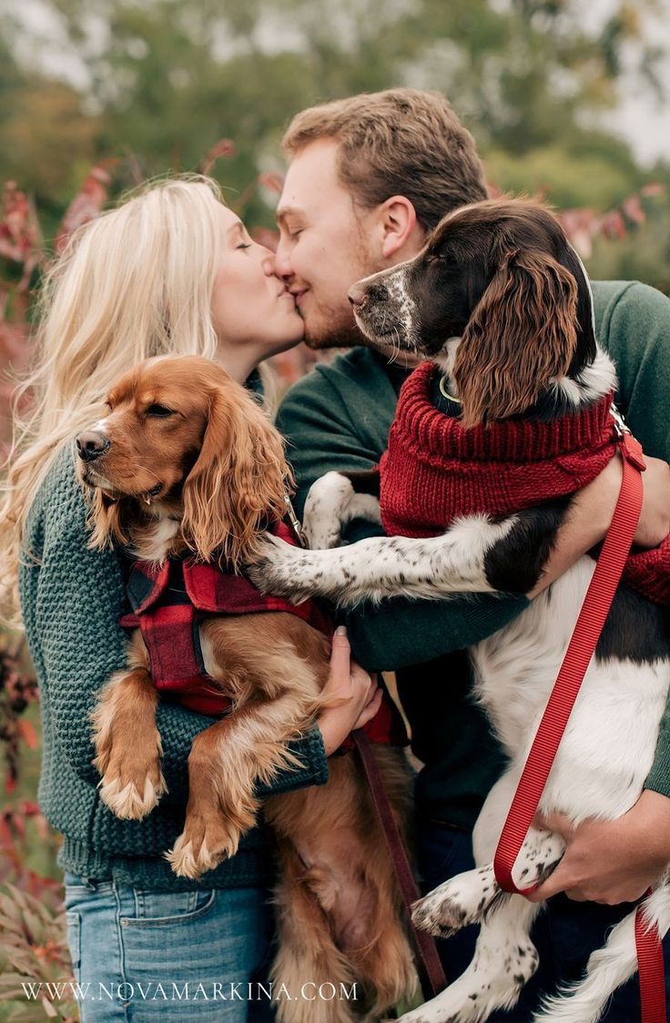 a man and woman kissing with two dogs