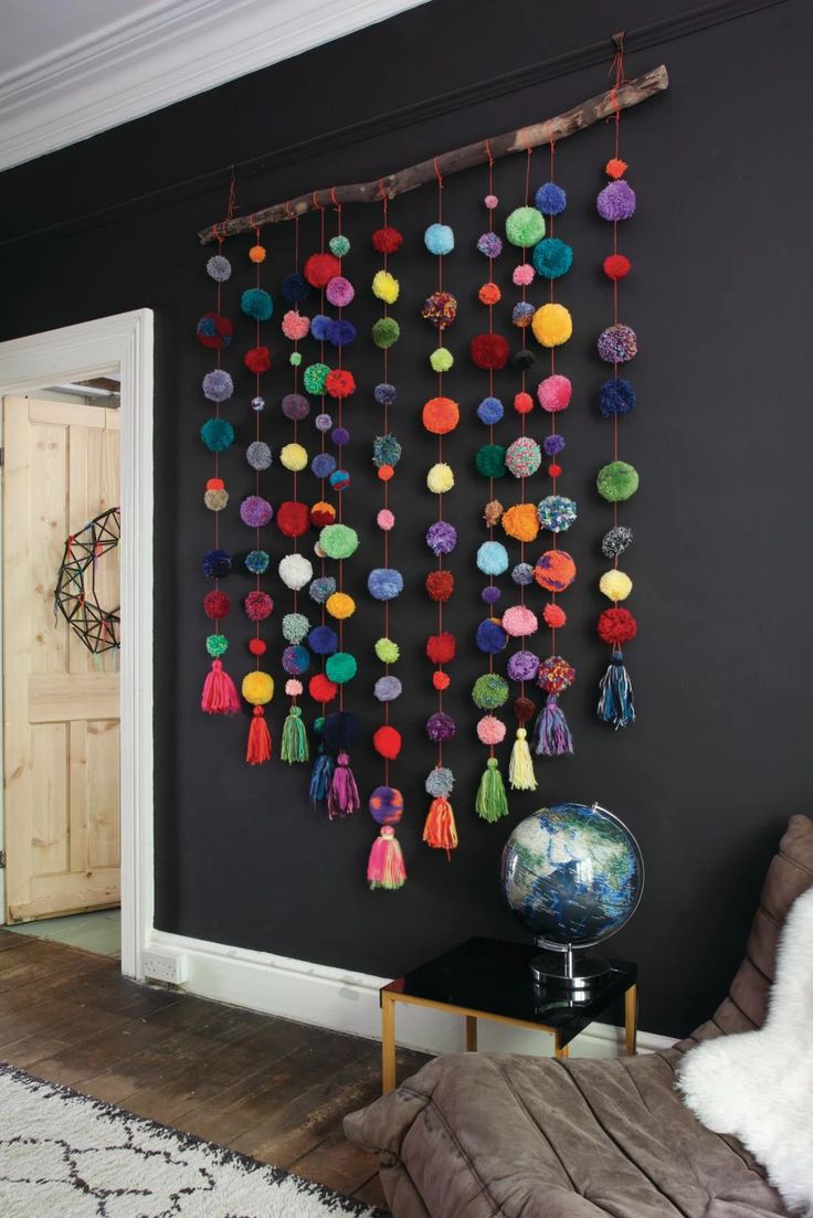 a room with black walls and lots of pom poms hanging on the wall