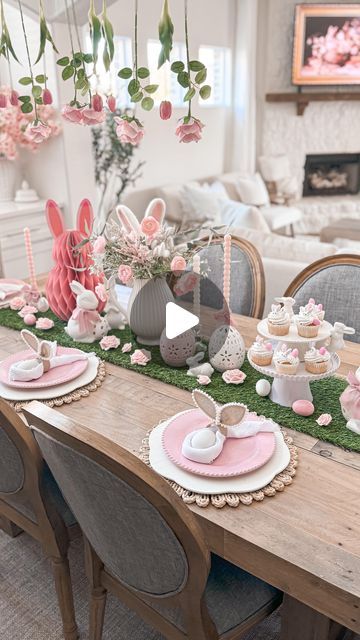 a dining room table set for easter with bunny decorations and pink napkins on it