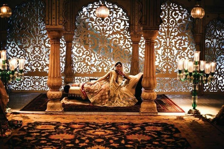 a woman sitting on top of a bed in a room filled with candles and lights