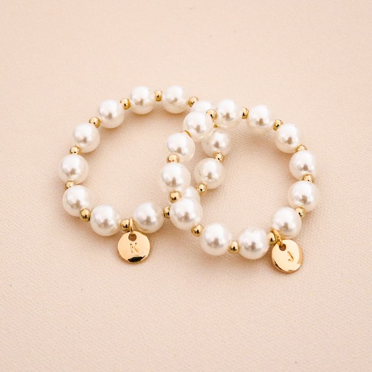 two bracelets with white pearls and gold charms