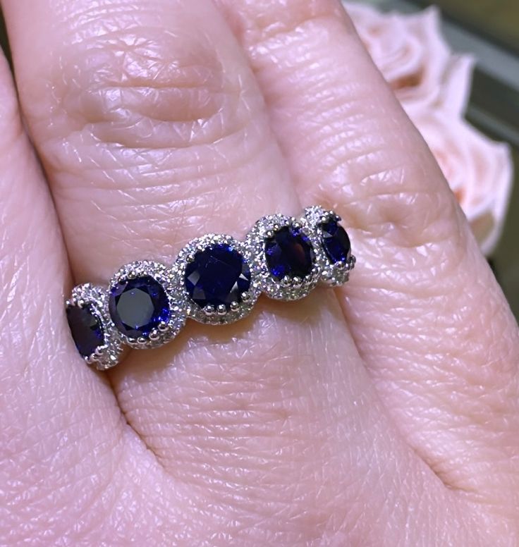 a woman's hand holding a ring with three blue sapphires on the side