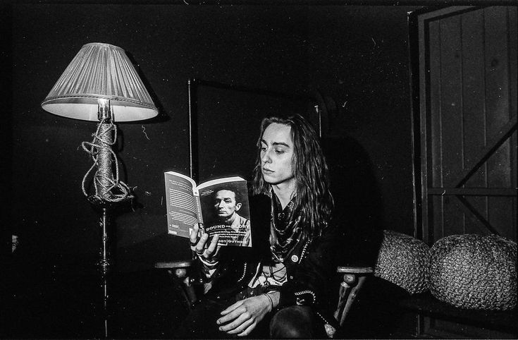 a black and white photo of a woman reading a book with a lamp in the background