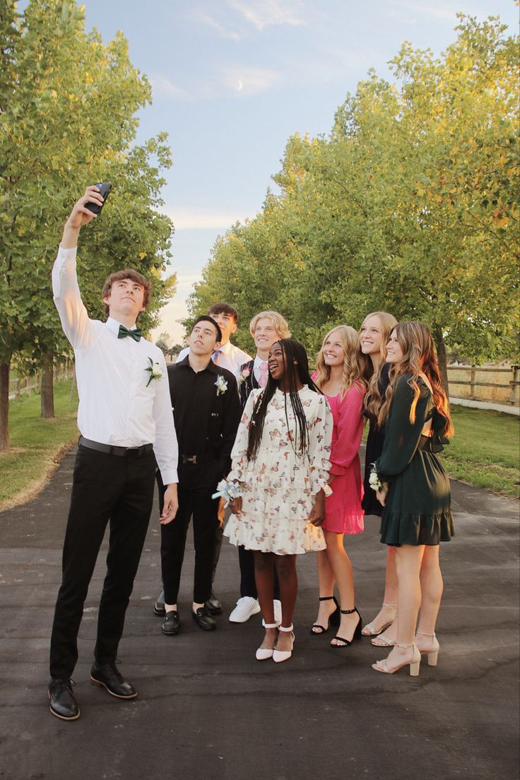 a group of people standing next to each other on a road with trees in the background