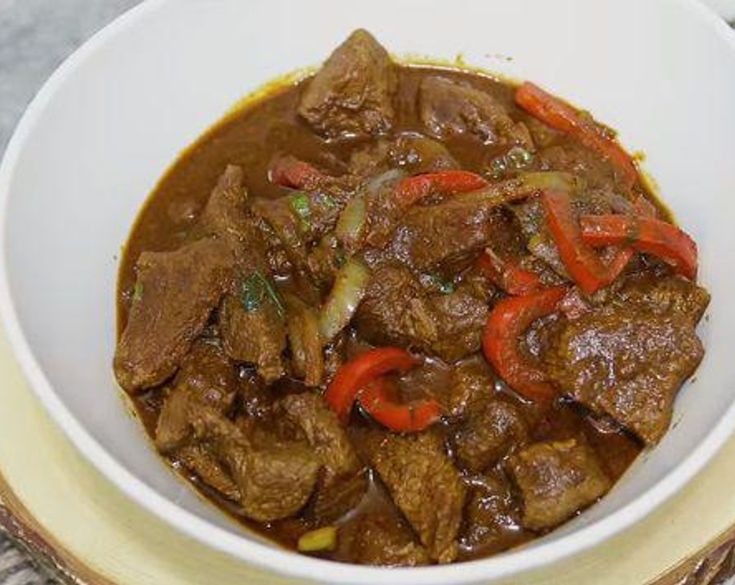 a white bowl filled with beef and peppers