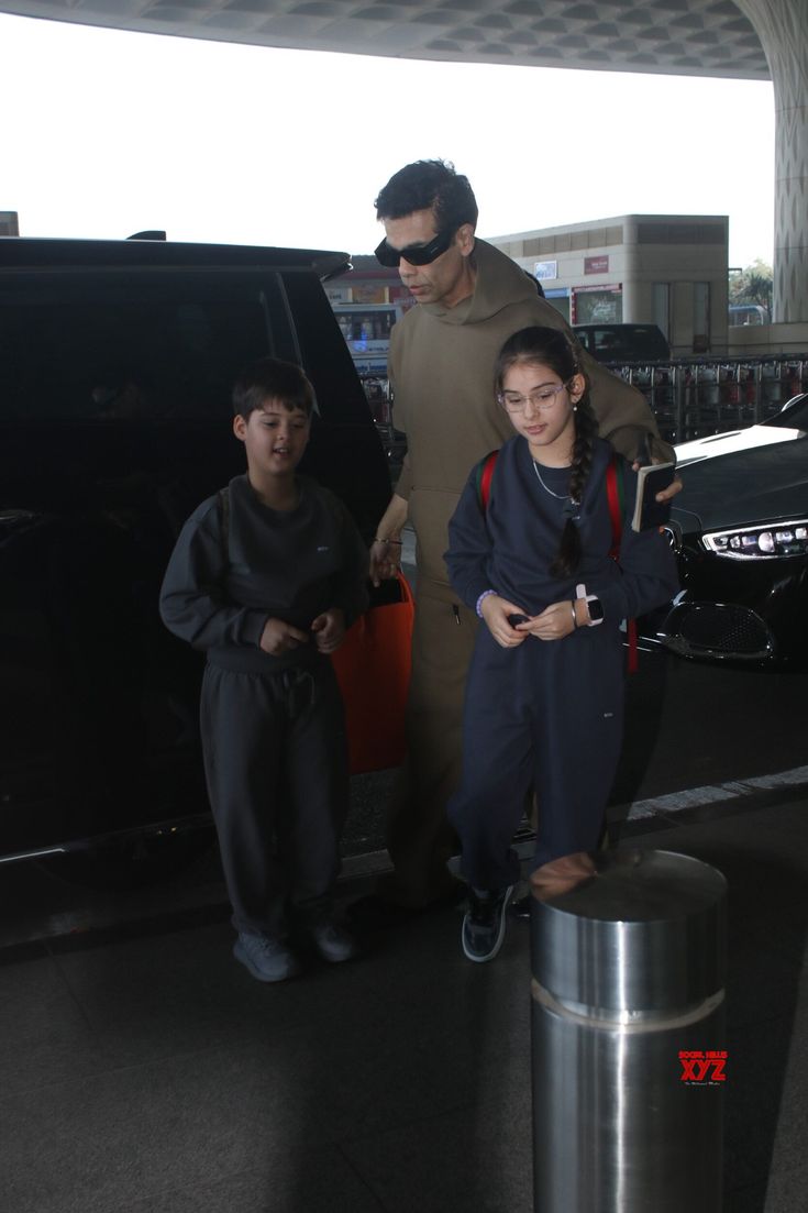 a man and two children standing in front of a car at an air port terminal