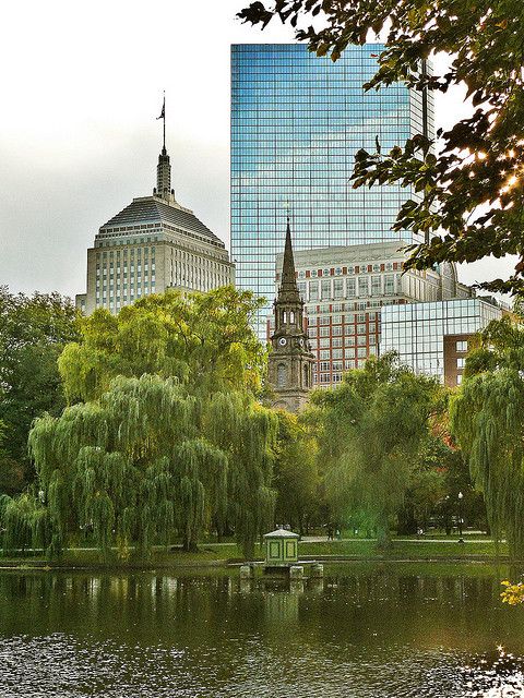 there is a small boat in the water near some trees and buildings on the other side of the lake