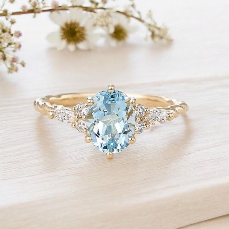 a ring with an oval blue topaz surrounded by small white diamonds on a wooden surface