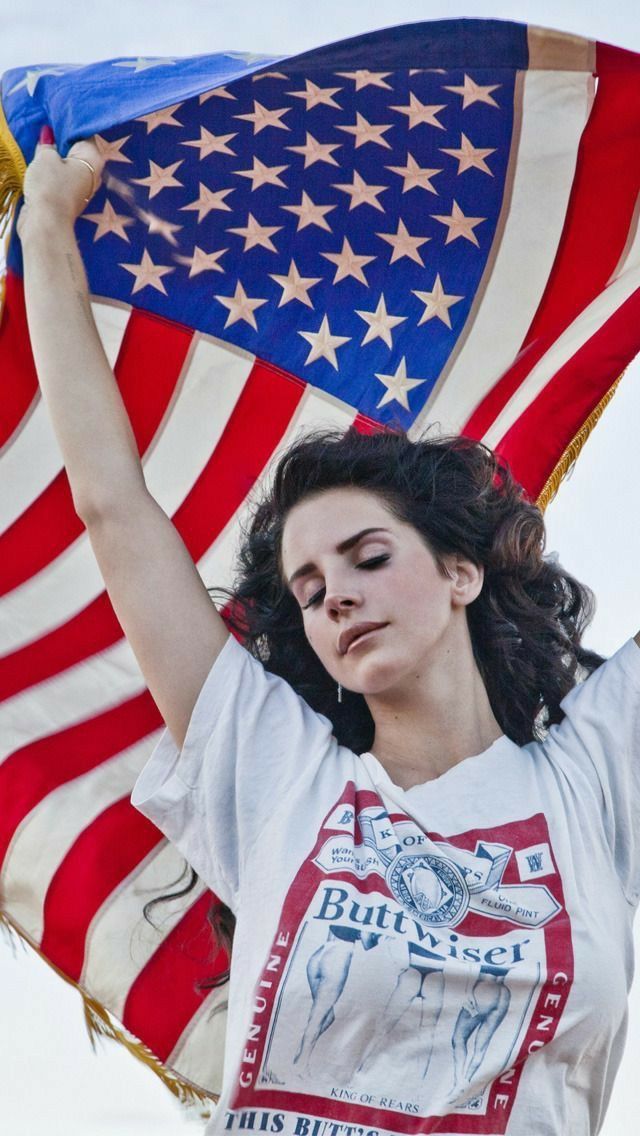 a woman holding up an american flag in front of her head and arms with both hands