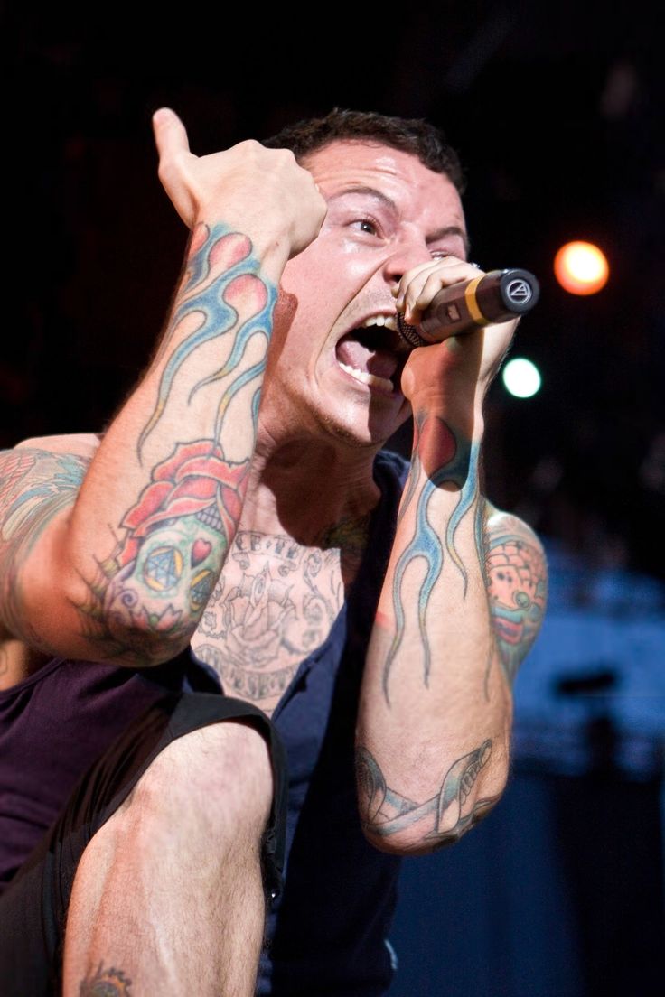 a man with tattoos singing into a microphone