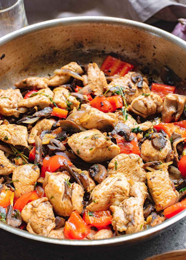 a pan filled with chicken, peppers and mushrooms