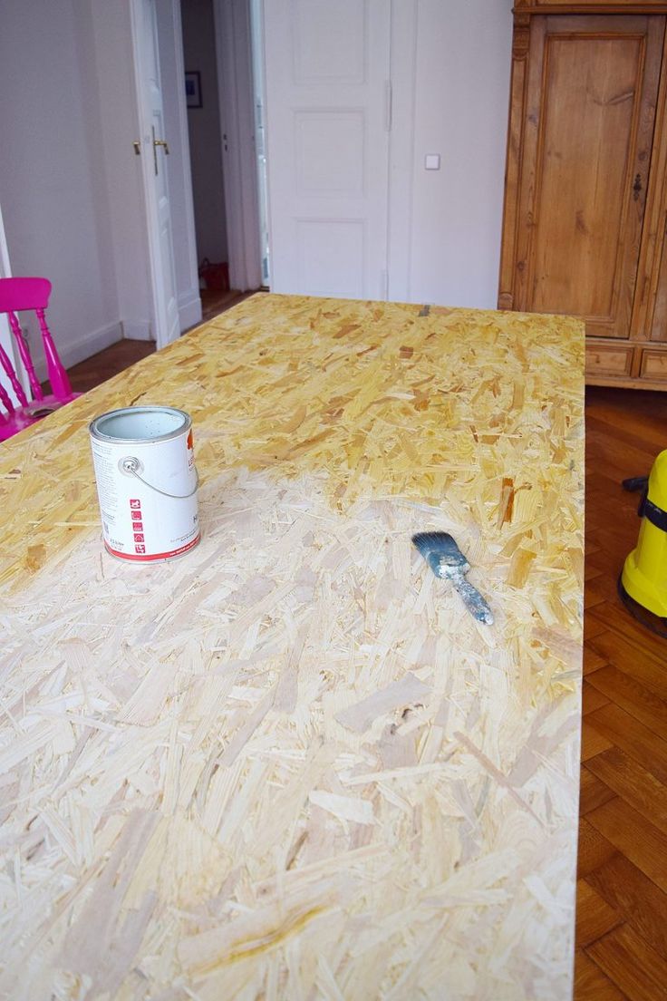 a bucket and paint can on top of a table in a room with hard wood flooring