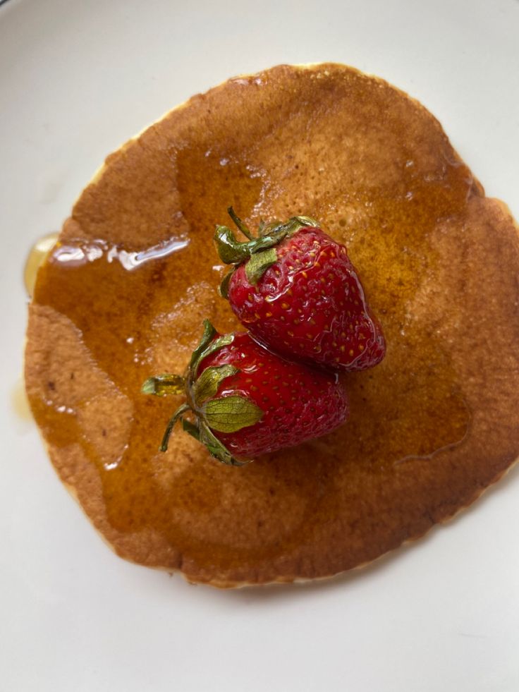 two strawberries sit on top of a pancake