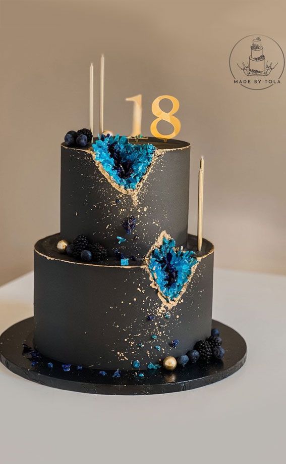 a three tiered cake with blue and black frosting on the top is decorated with gold numbers