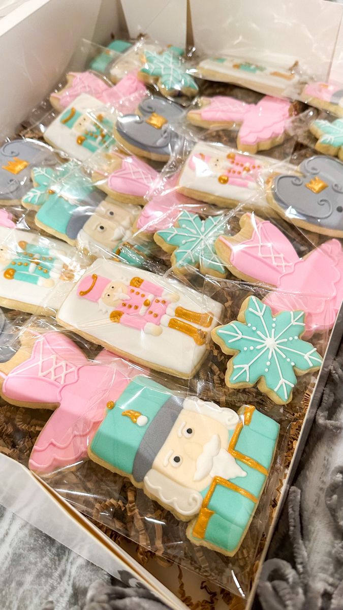 a box filled with lots of decorated cookies in different colors and designs on top of a table