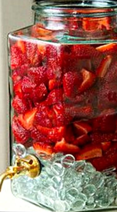 a glass jar filled with sliced strawberries on top of a counter