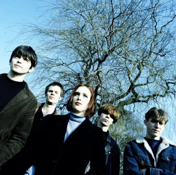 a group of young men standing next to each other in front of a bare tree