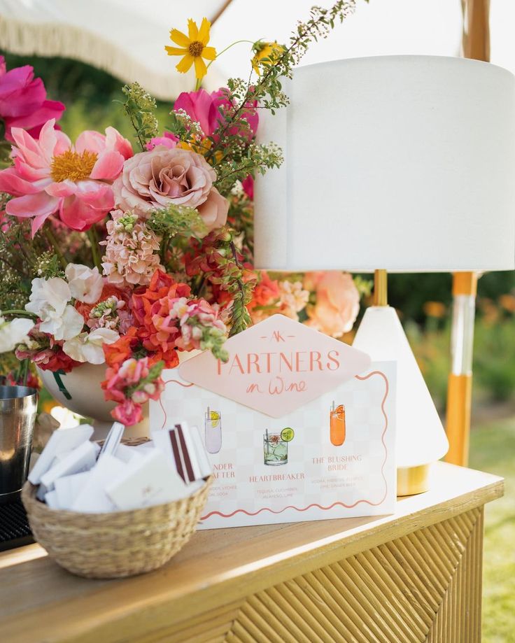 an arrangement of flowers and personal items on a wooden table with a lamp in the background