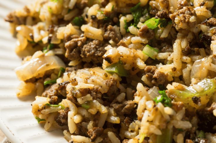 rice with meat and green onions on a white plate, ready to be eaten for lunch