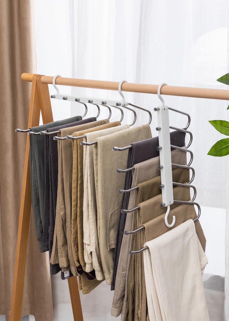 clothes hanging on a rail in front of a window with white curtains and a green plant