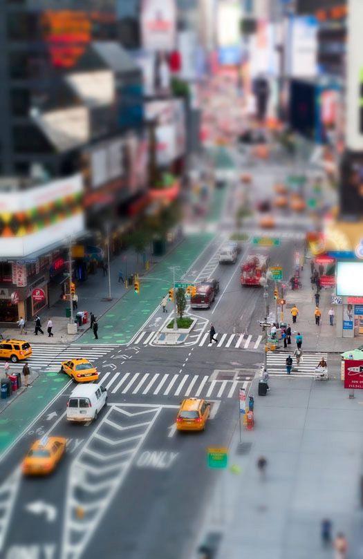 an aerial view of a busy city street with taxi cabs, pedestrians and people