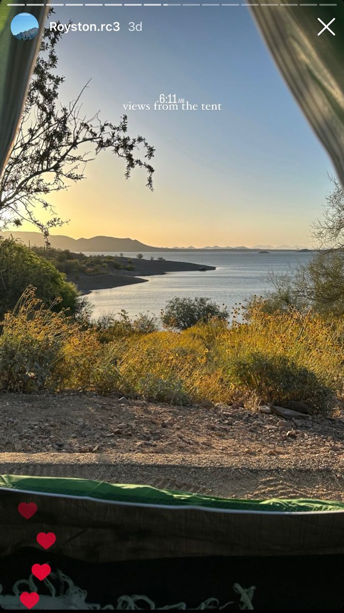 the view from inside a tent looking out at water and land, with trees in the foreground