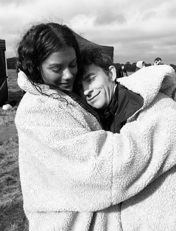 two people wrapped up in blankets on a field