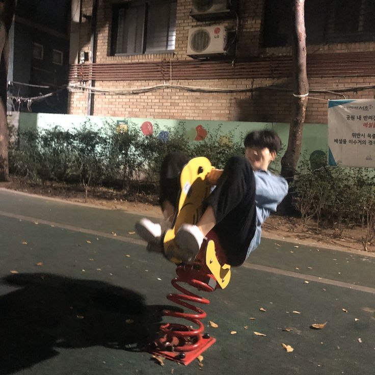 a young man riding a skateboard on top of a red and yellow object in the street