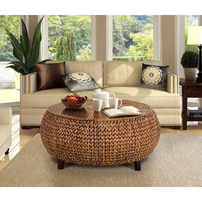 a wicker coffee table sitting on top of a rug in front of a couch