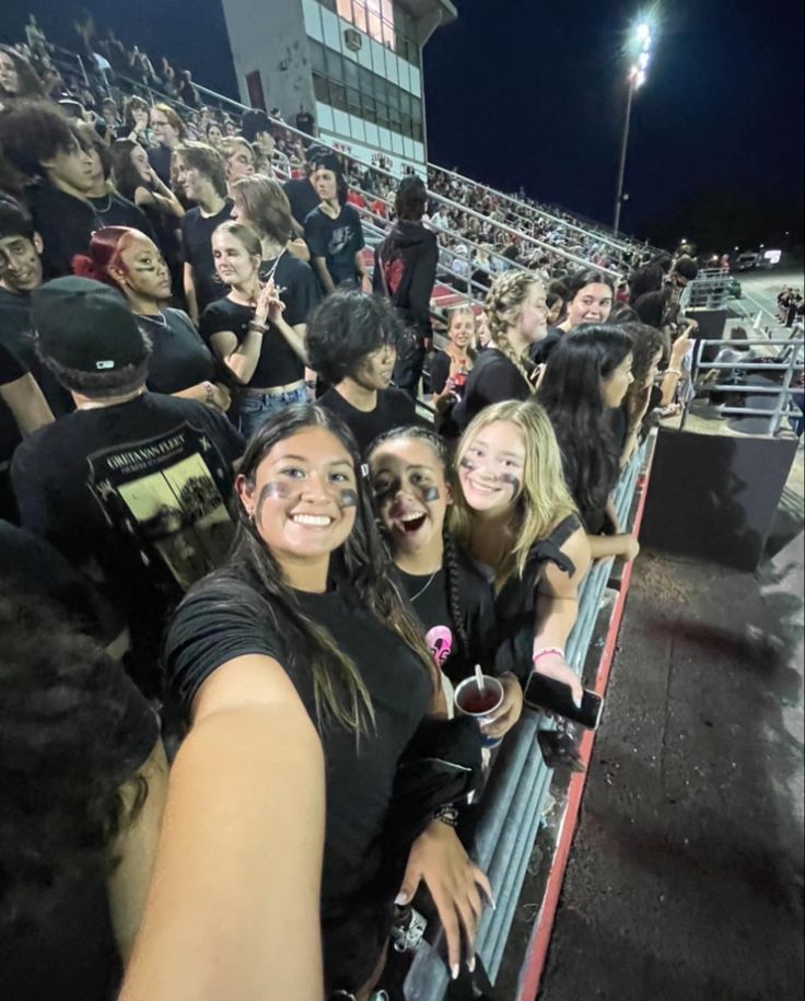 a group of young people standing next to each other in front of a bleachers