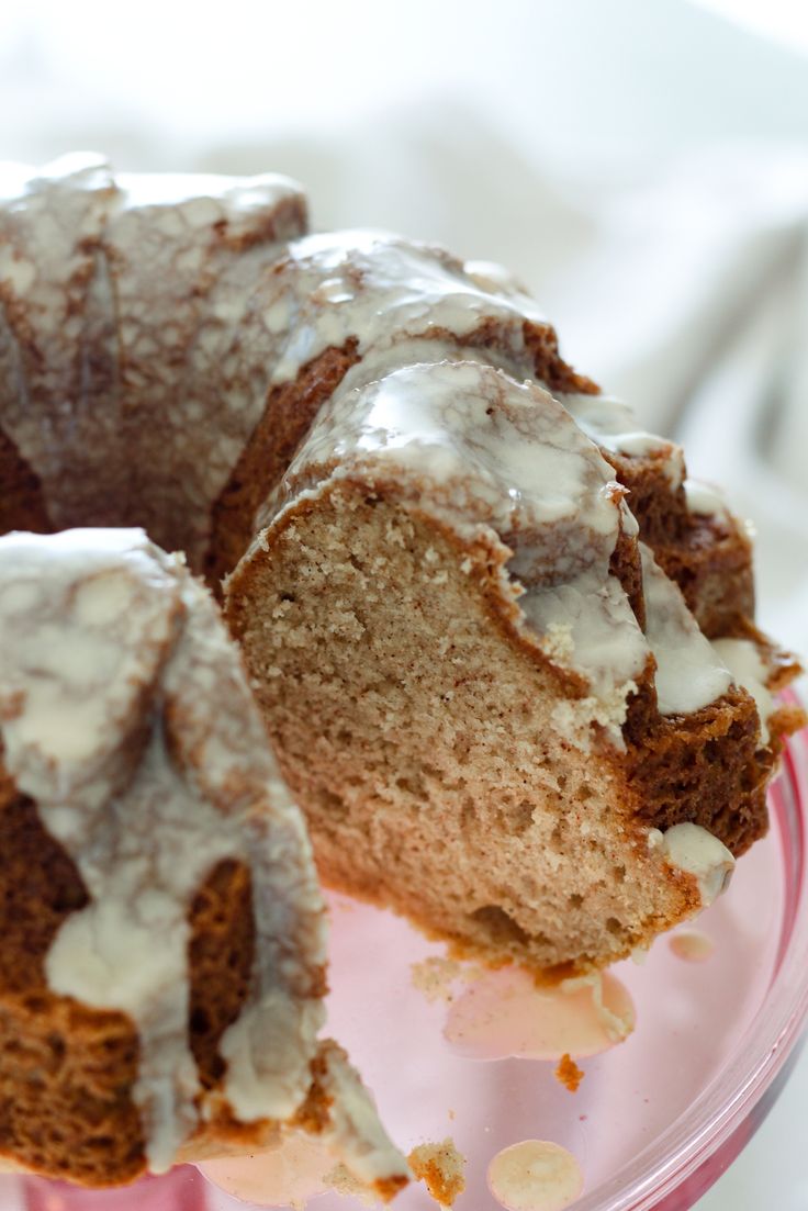 a bundt cake sitting on top of a glass plate with frosting and icing