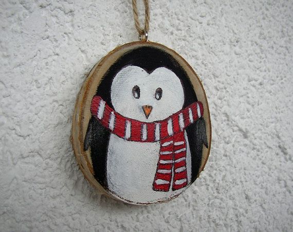 a penguin with a scarf on it's neck hanging from a wood slice ornament