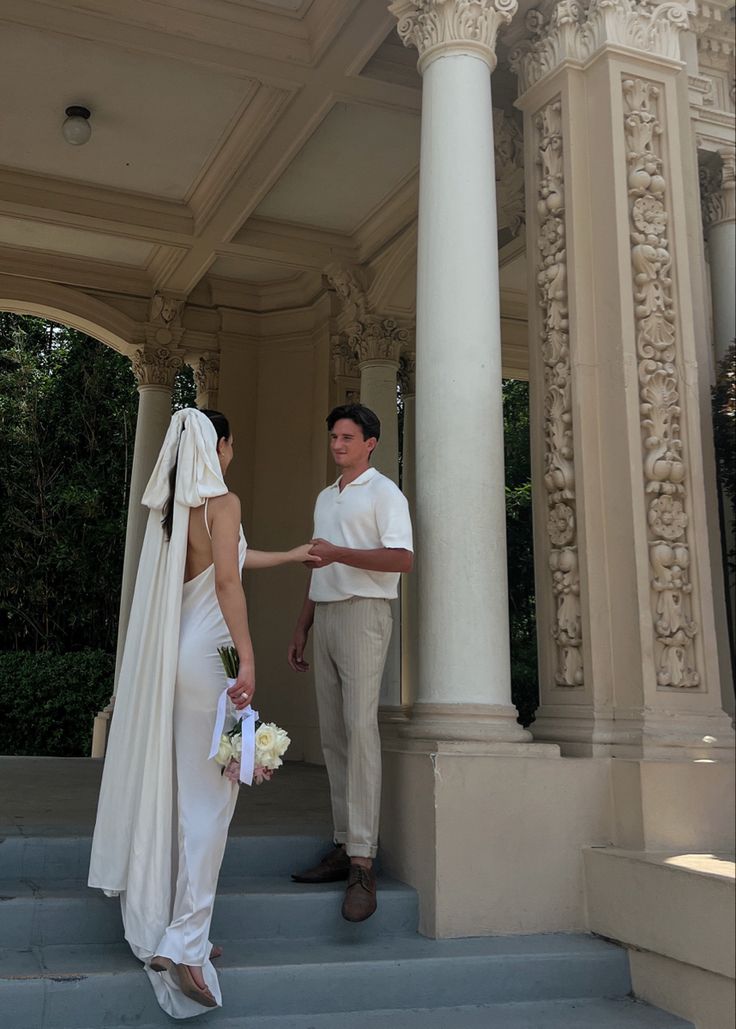 a bride and groom are standing on the steps in front of a gazebo holding hands