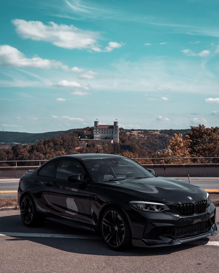 a black car is parked on the side of the road in front of some hills