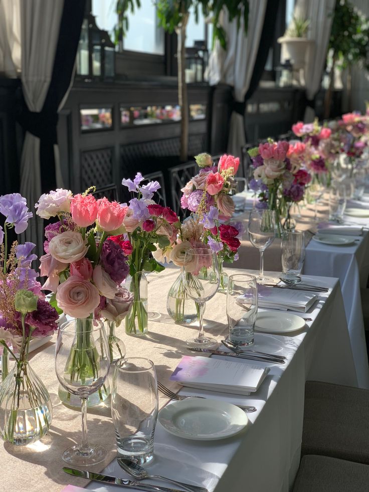 a long table with many vases filled with flowers