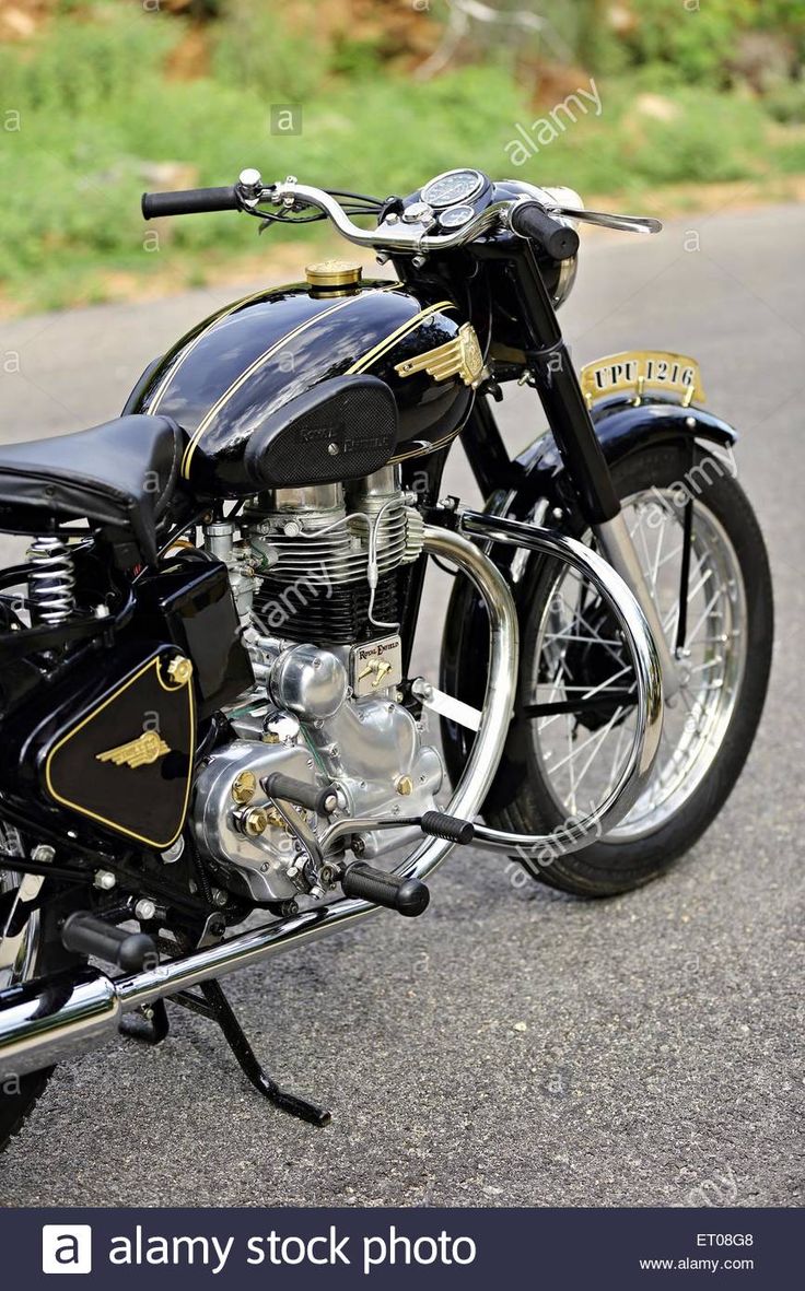 a black and gold motorcycle parked on the side of the road with grass in the background