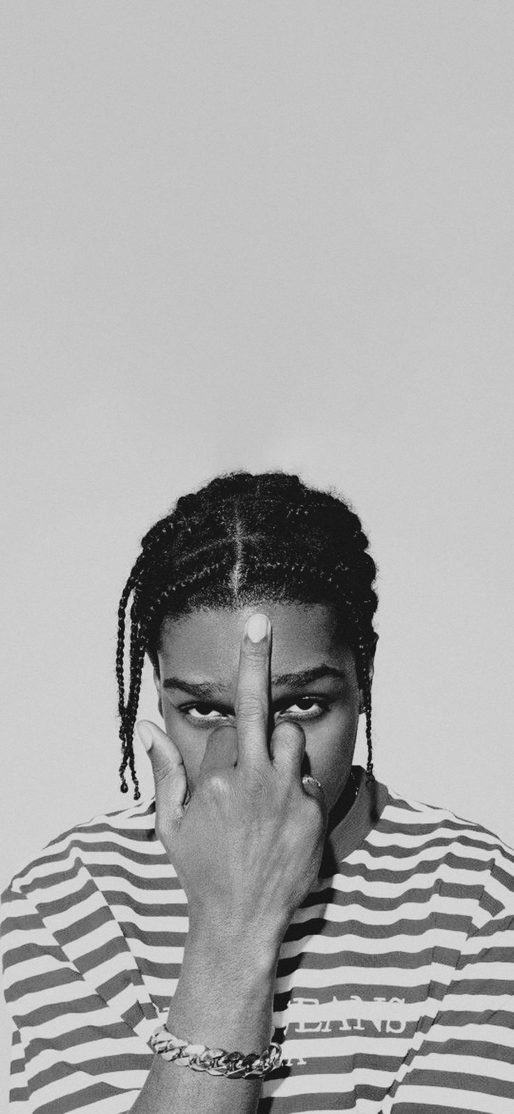 a black and white photo of a woman covering her face with her hands, looking at the camera