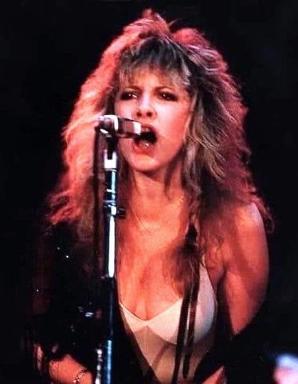 an image of a woman singing on stage with a microphone in front of her face