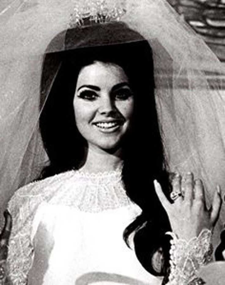 an old photo of a woman wearing a wedding dress and holding her veil over her head