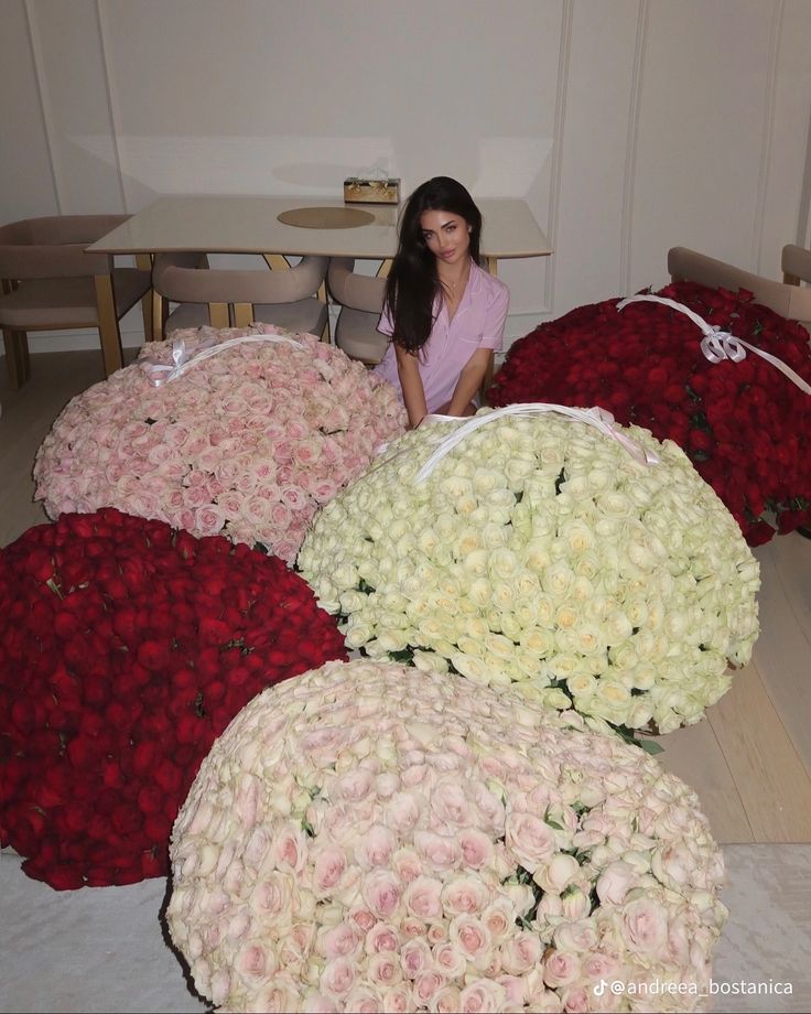 a woman sitting on the floor surrounded by large bouquets of white and pink roses