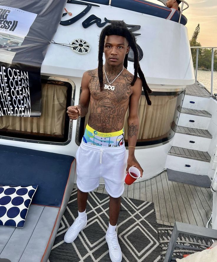 a man with dreadlocks standing in front of a boat