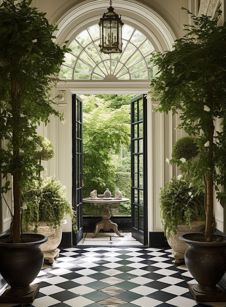 an entry way with potted plants and a table in the center is surrounded by black and white checkered tiles